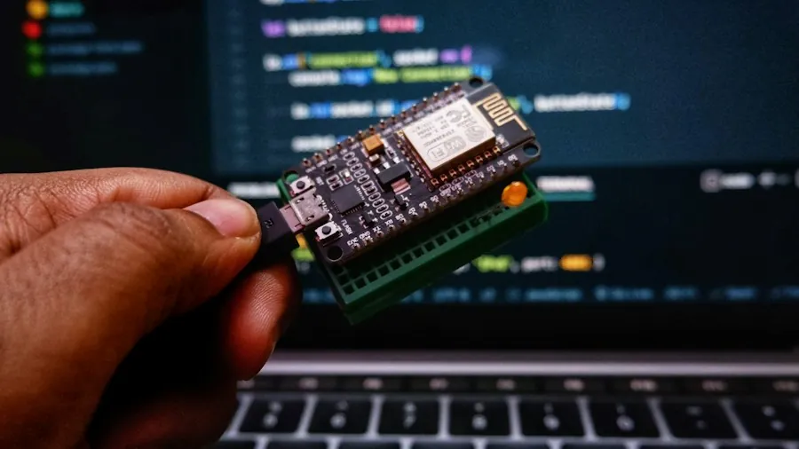 Hand holding an IoT sensor board in front of code