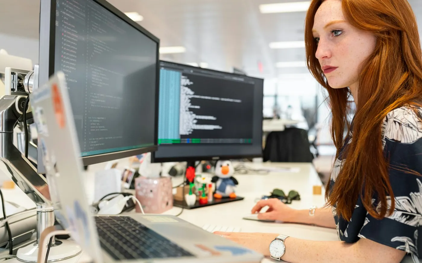 A software developer working with code on two monitors